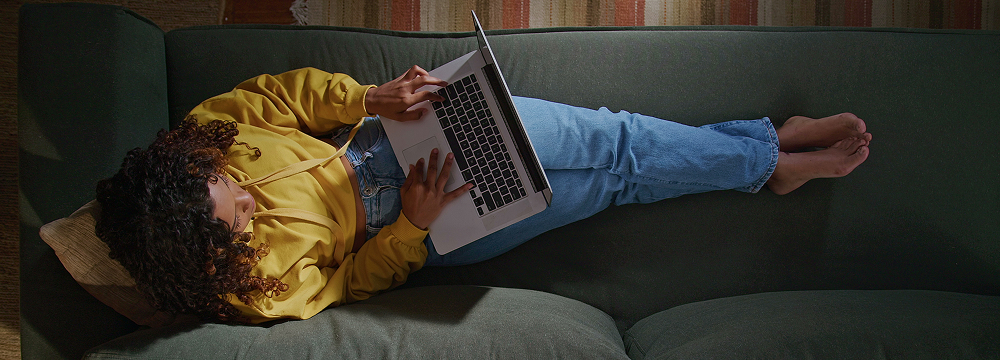 Happy woman sitting on a sofa looking at her laptop