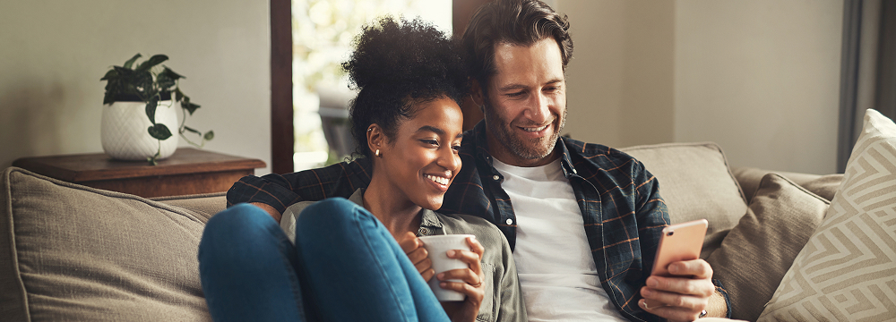 Happy couple sitting together looking at the man's phone