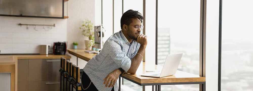 Happy man looking at computer by a window