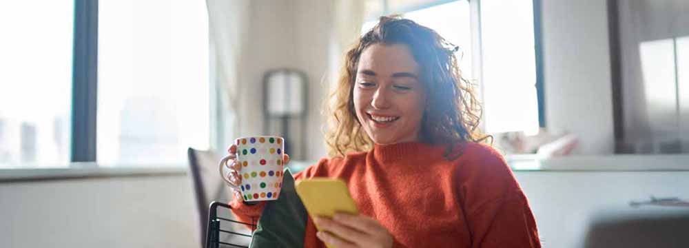 Happy woman sitting on couch looking at her phone