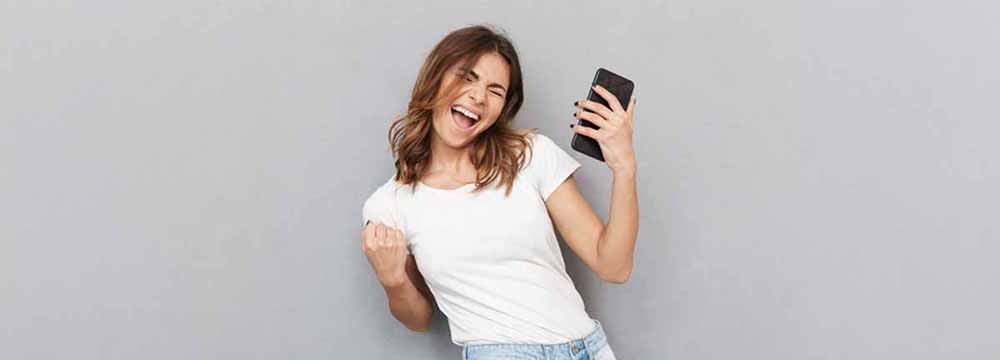 Happy woman fist pumping while holding her phone