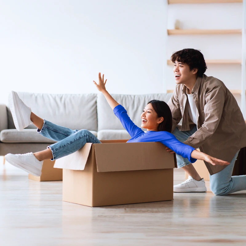 Smiling couple playing with moving boxes in their new home.