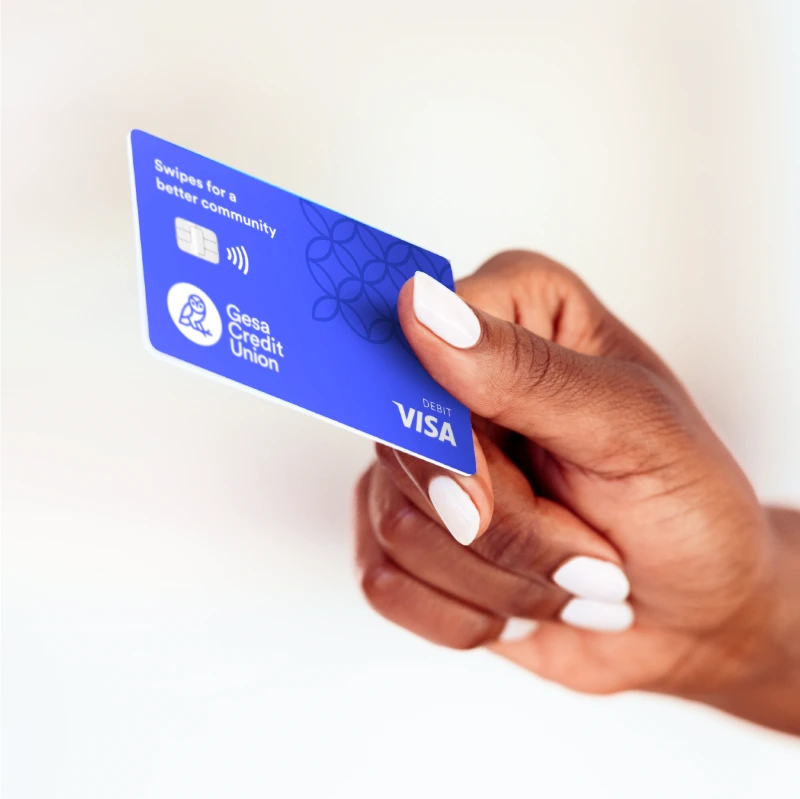 Hand holding a blue Gesa Credit Union Visa debit card with contactless payment symbol.