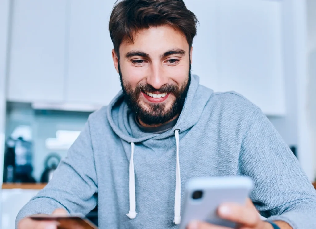 Man smiling while using his phone at home