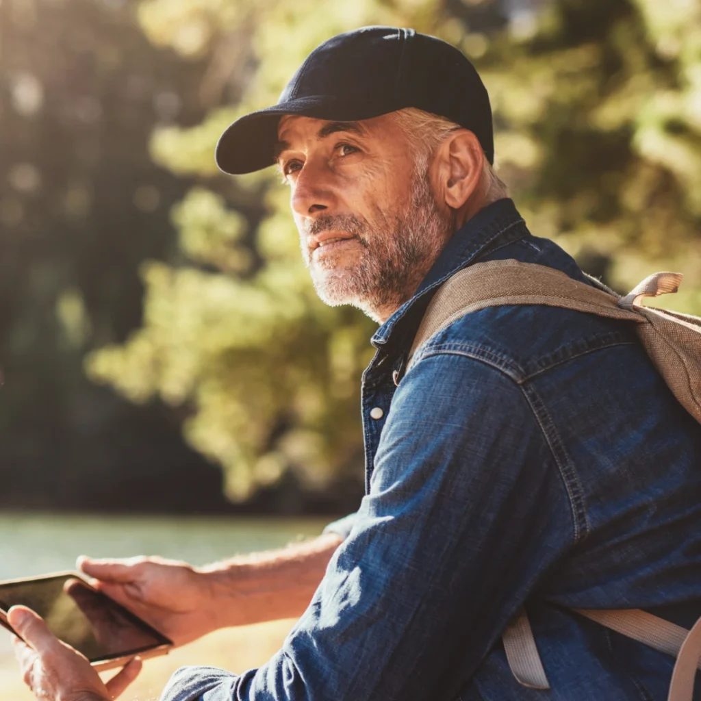 Man sitting outdoors with tablet and backpack