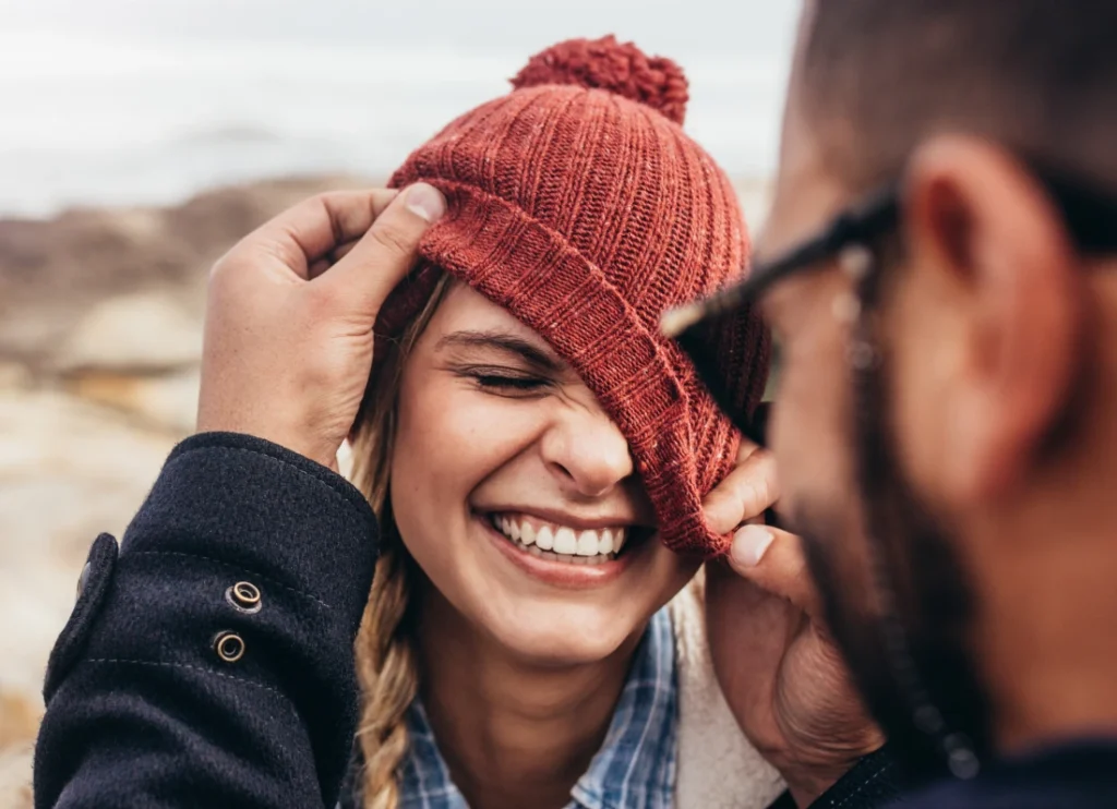 Couple laughing together while adjusting a beanie